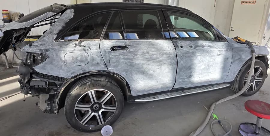 Auton kylki pohjatöissä korjaamon hallissa